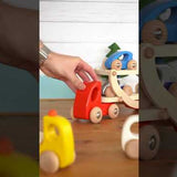 Close up of hand playing with the Bajo wooden transporter lorry toy on a wooden table