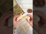 Looking down at child using the Plan Toys wooden knife to cut the wooden bread toy set on a wooden worktop