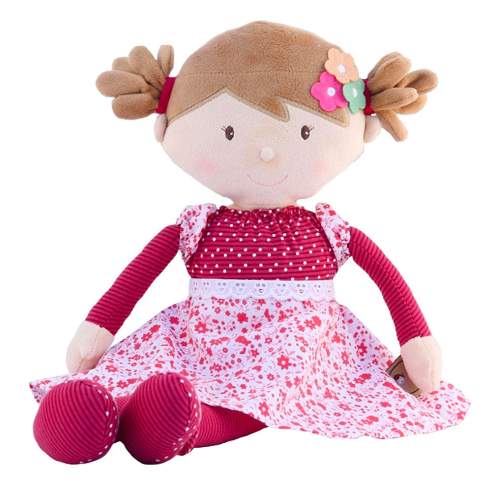The Bonikka Scarlett rag doll is a soft toy doll with light brown fleece hair in pig tails and a deep pink spotty and floral dress. sat down with white background.