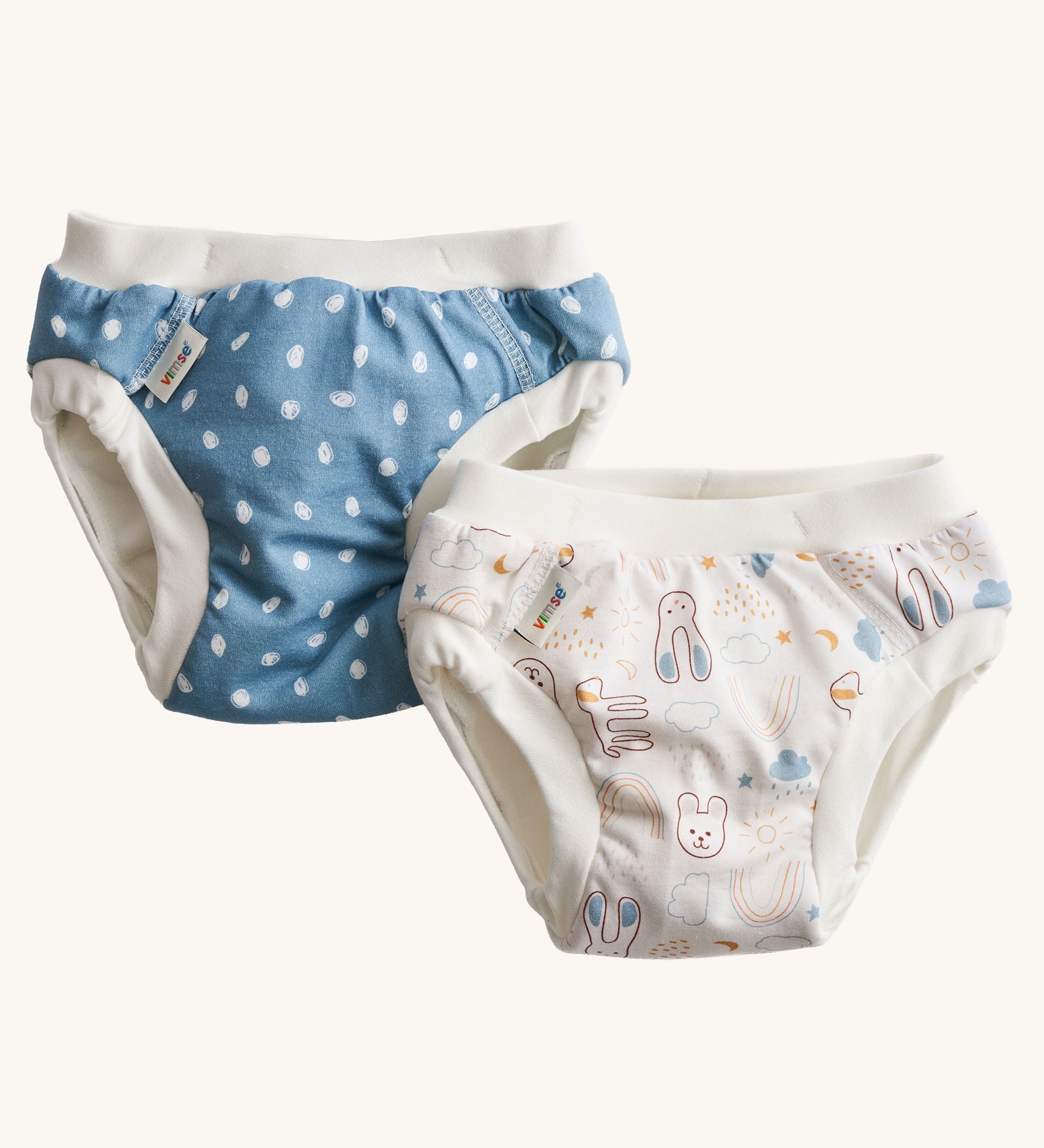 A pack of two Imse Vimse Blue and Teddy design reusable Training Pants for toddlers weighing from 16-20 kg available at Babipur. Two comfortable Cotton reusable training pants. The one on the left is blue with white scribbled sports, and the one on the right is white with colourful rabbits, bears, dogs, rainbows, clouds.