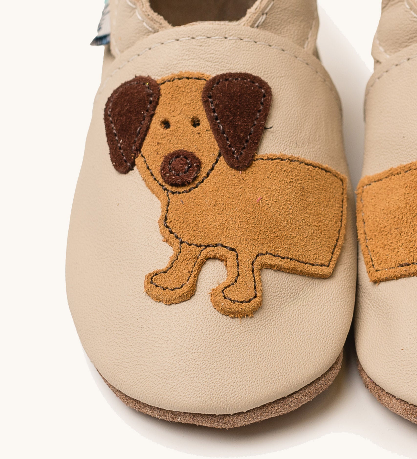 A close up of the Inch Blue cream dash shoes available at Babipur showing the brown suede cut out dachshund design