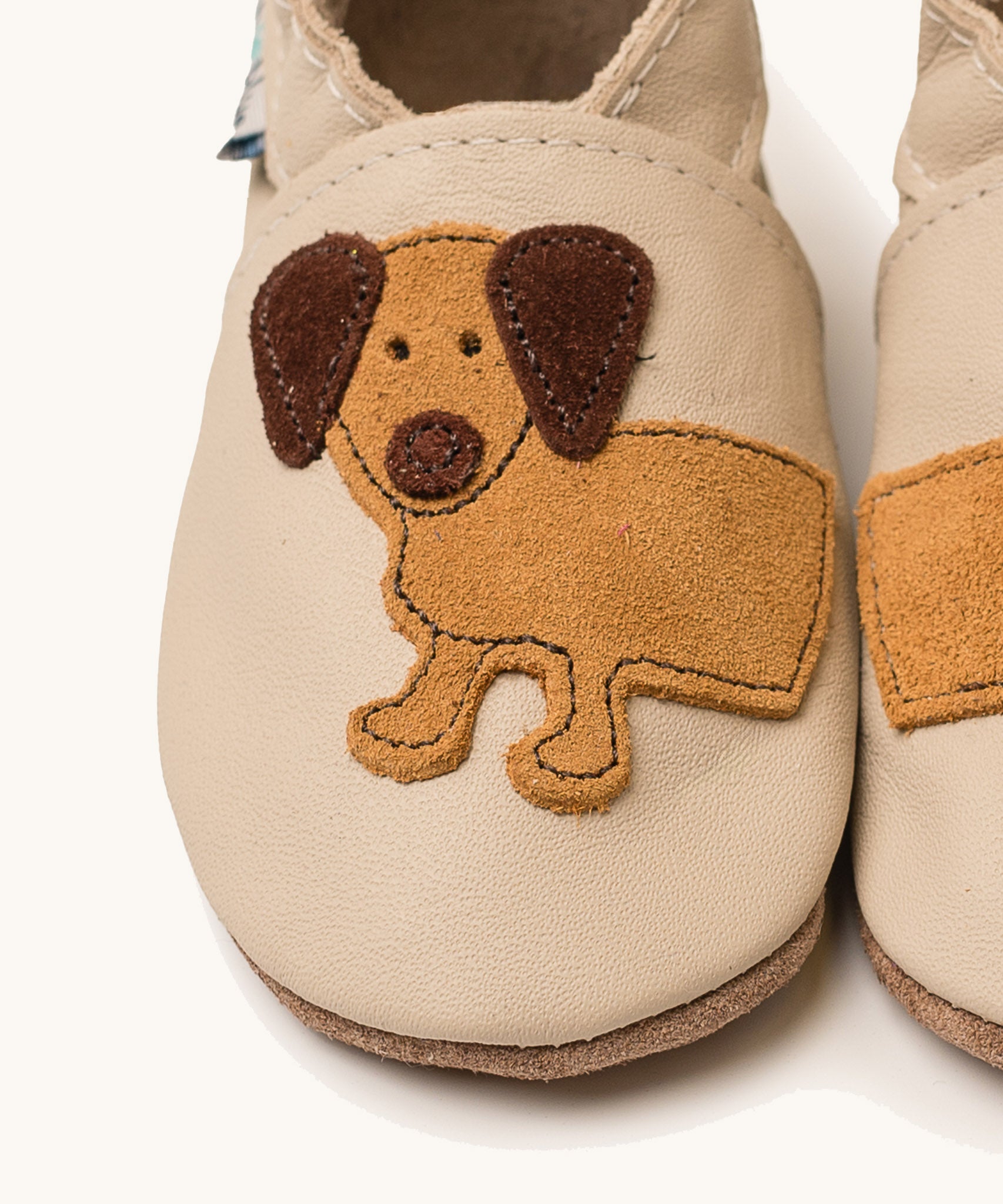A close up of the Inch Blue cream dash shoes available at Babipur showing the brown suede cut out dachshund design