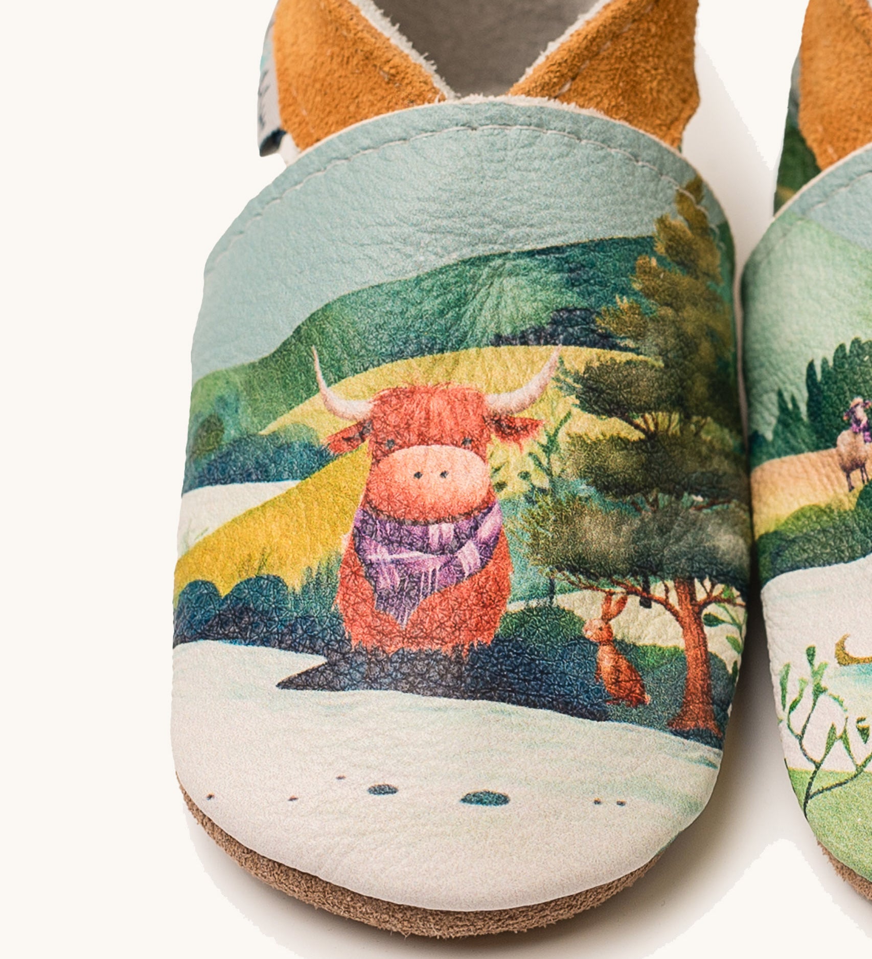 A close up of the Inch Blue highland cow shoes available at Babipur showing  a closer look at the highland cow design