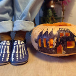 Child wearing Inch Blue Leather Baby Shoes - Bones stood next to a carved pumpkin on wooden flooring