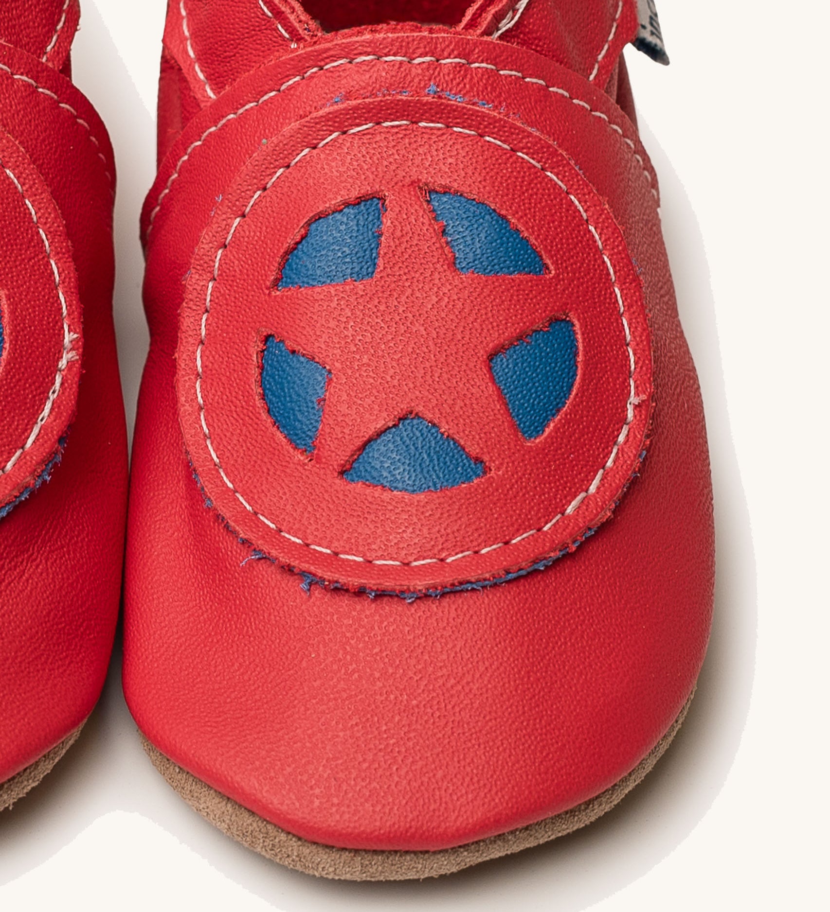 A close up of the Inch Blue superkid red baby shoes available at Babipur. Showing the red and blue star shield design