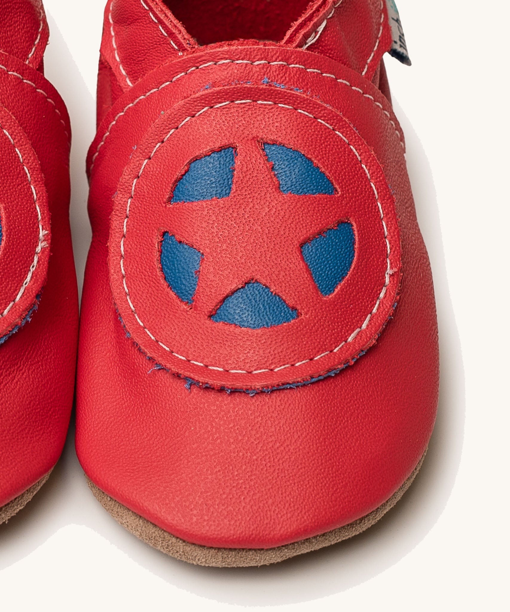 A close up of the Inch Blue superkid red baby shoes available at Babipur. Showing the red and blue star shield design