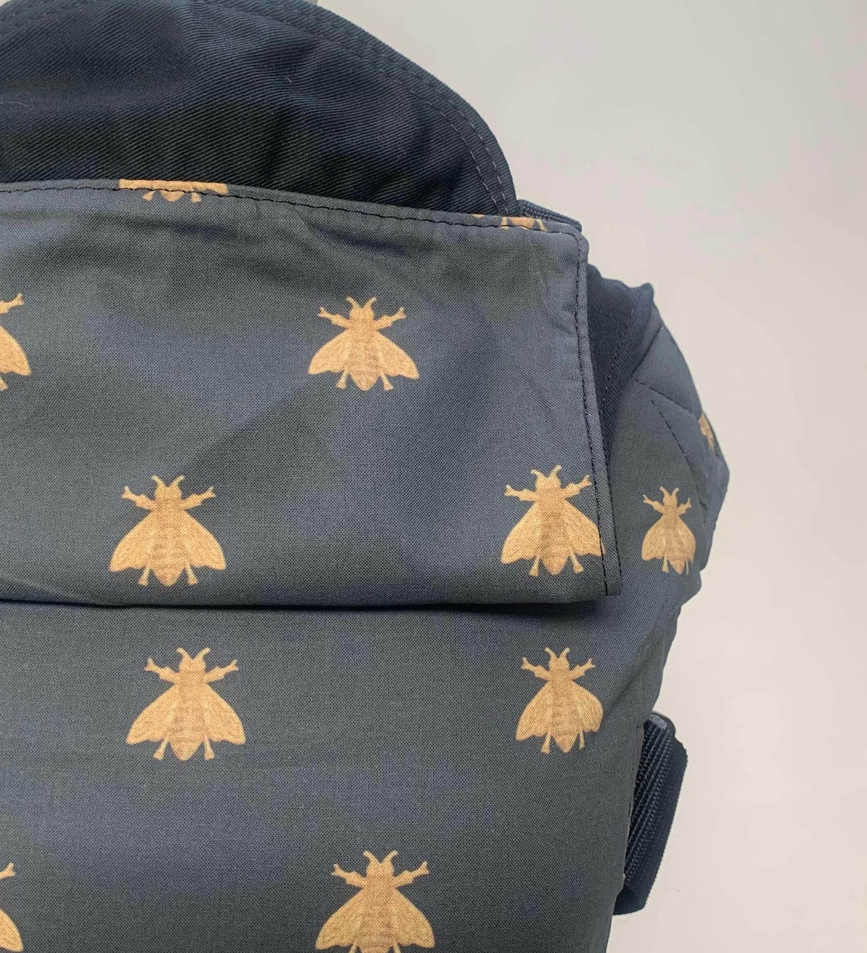 A close up of the golden bee design and hood detail on the Integra bee baby carrier available at a Babipur.  