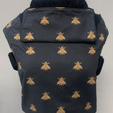 Integra bee design baby carrier available at a Babipur.  A navy carrier with a golden bee design. Features a small hood for head protection.