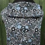 Integra Copenhagen baby carrier available at a Babipur a dark coloured carrier with a white flower design. Features a small hood for head protection.