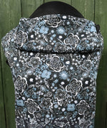 Integra Copenhagen baby carrier available at a Babipur a dark coloured carrier with a white flower design. Features a small hood for head protection.