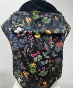 Integra flower garden baby carrier available at a Babipur a dark coloured carrier with a vintage inspired flower and butterfly design. Features a small hood for head protection.