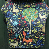 Integra frolic baby carrier available at a Babipur a dark coloured carrier with a playful design of a rabbit fox and various flowers. Features a small hood for head protection.