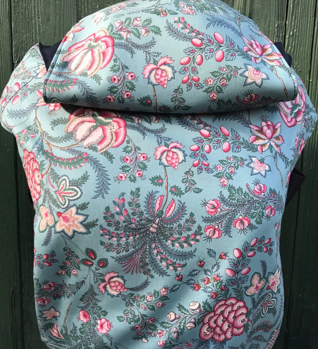 Integra Martha baby carrier available at a Babipur a light blue coloured carrier with a vintage pink floral design. Features a small hood for head protection.