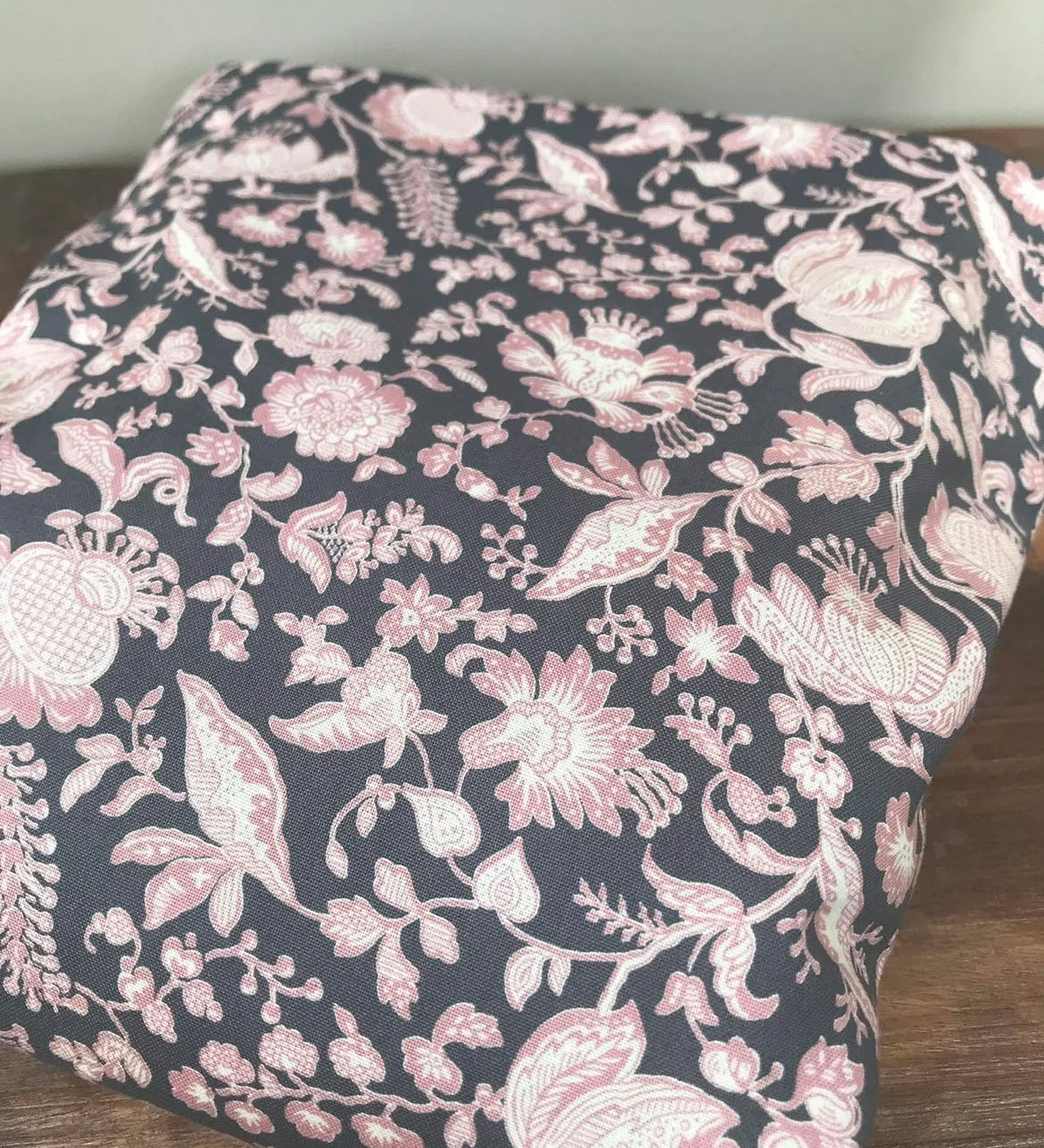 Integra Peta baby carrier available at a Babipur a dark coloured carrier with a pink floral design. Features a small hood for head protection.