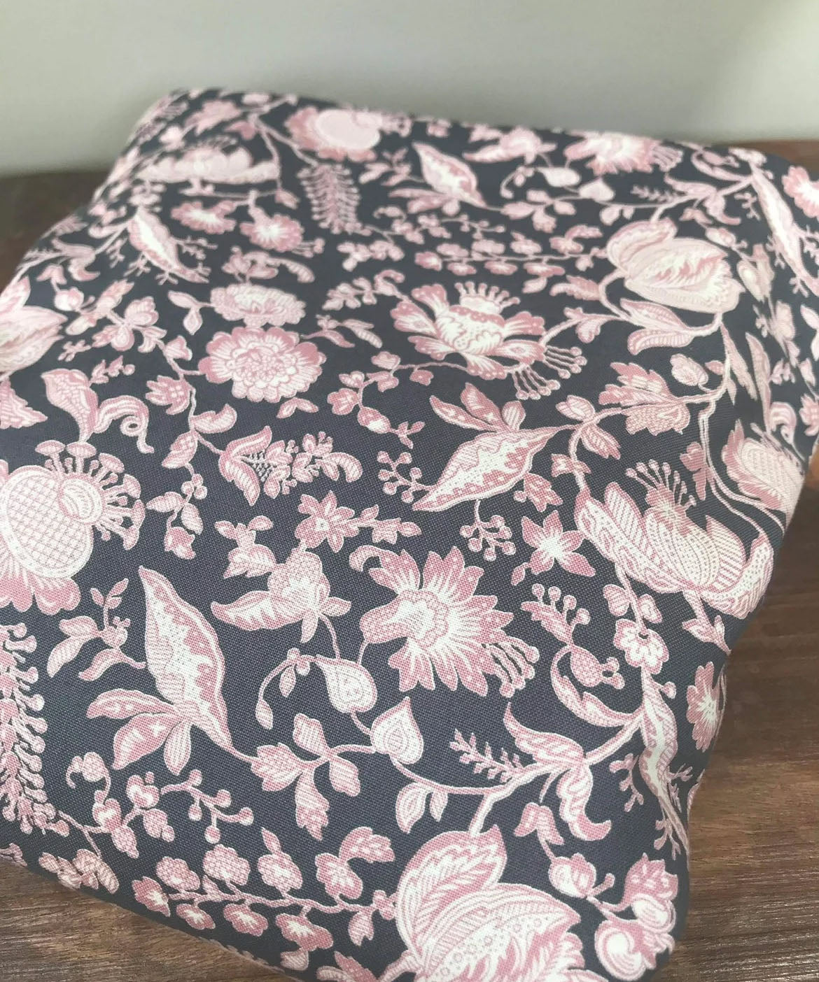 Integra Peta baby carrier available at a Babipur a dark coloured carrier with a pink floral design. Features a small hood for head protection.