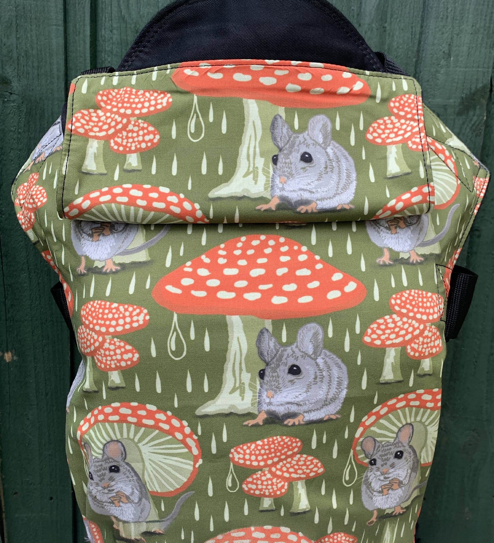 Integra shelter baby carrier available at a Babipur a green coloured carrier with a vintage mouse and toadstool design. Features a small hood for head protection.