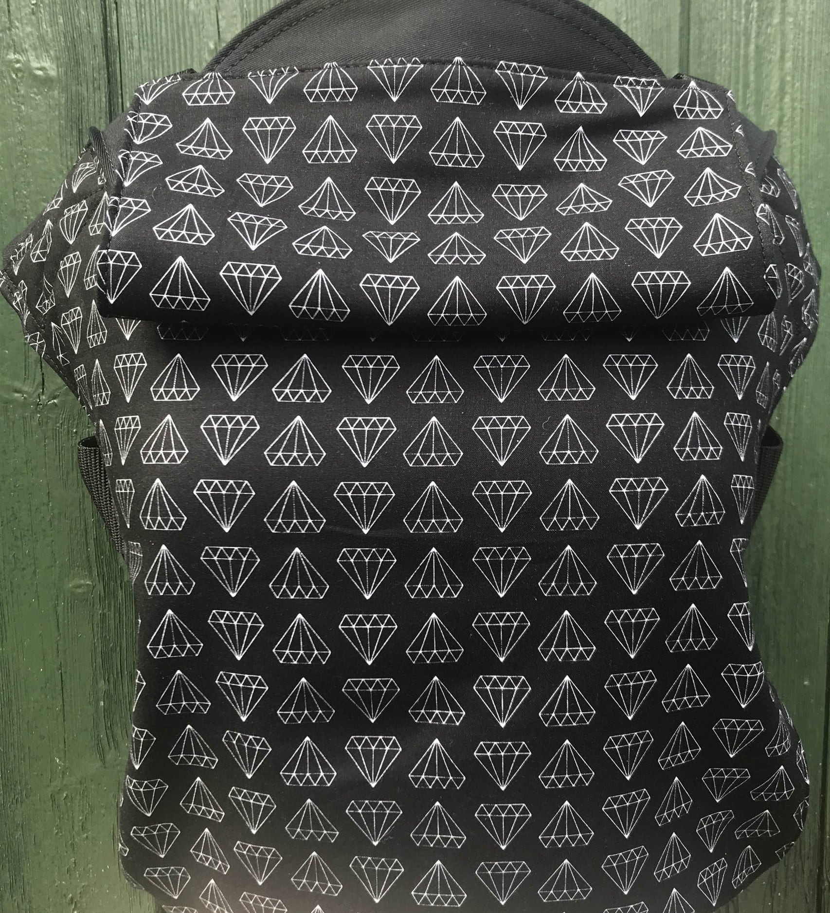 Integra shine bright design baby carrier available at a Babipur.  A black carrier with a geometric style diamond design. Features a small hood for head protection.