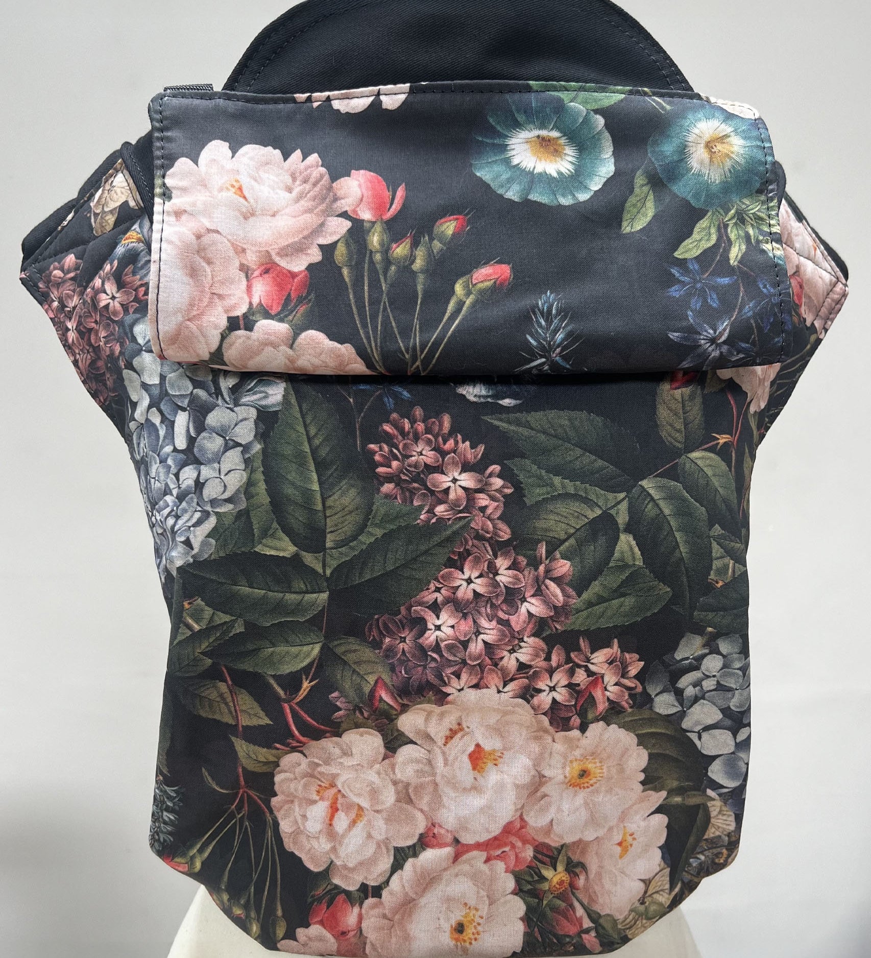 Integra vintage summer baby carrier available at a Babipur a dark coloured carrier with a vintage flower design. Features a small hood for head protection.