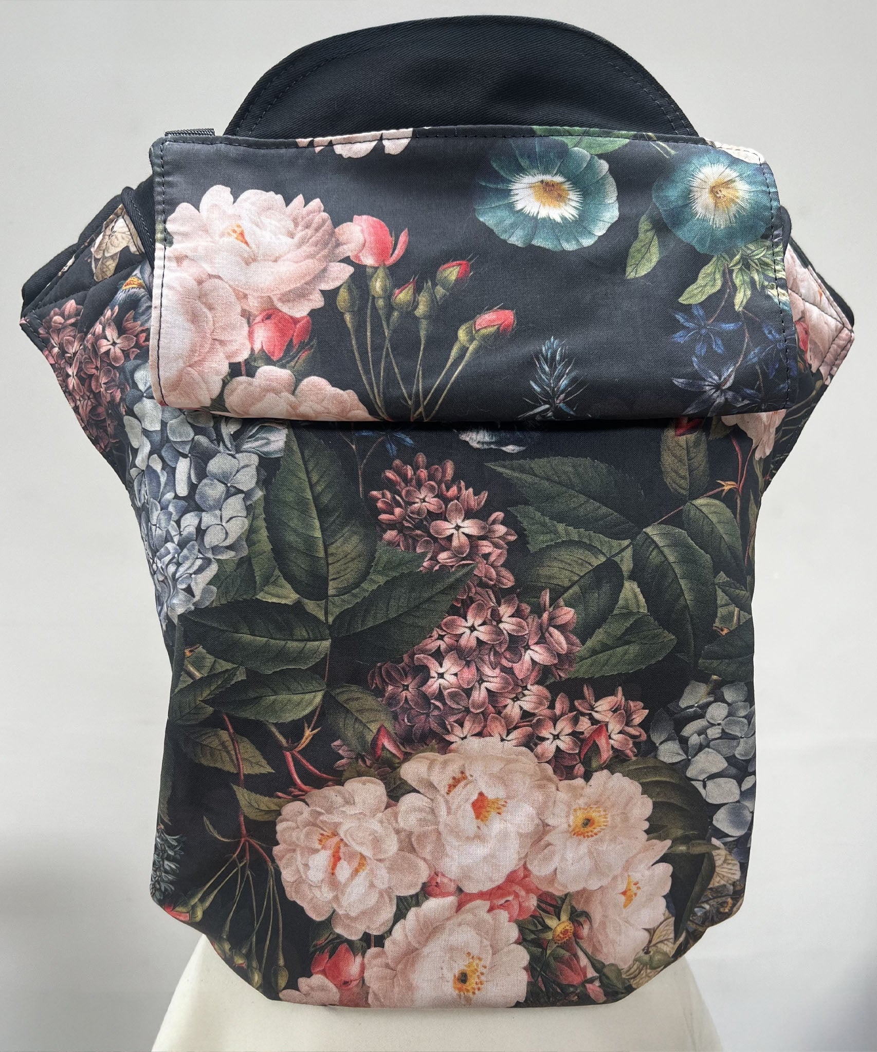 Integra vintage summer baby carrier available at a Babipur a dark coloured carrier with a vintage flower design. Features a small hood for head protection.