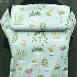 Integra viva baby carrier available at a Babipur a lightly coloured carrier with green house plants prints. Features a small hood for head protection.