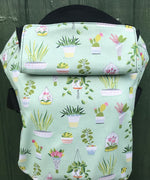 Integra viva baby carrier available at a Babipur a lightly coloured carrier with green house plants prints. Features a small hood for head protection.