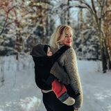 A mother carrying a baby outside in the Integra baby carrier in essential black available at Babipur.