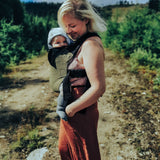 A mother and baby standing outdoors. Mother is carrying the bab in the Integra khaki texture linen baby carrier available at a Babipur. 