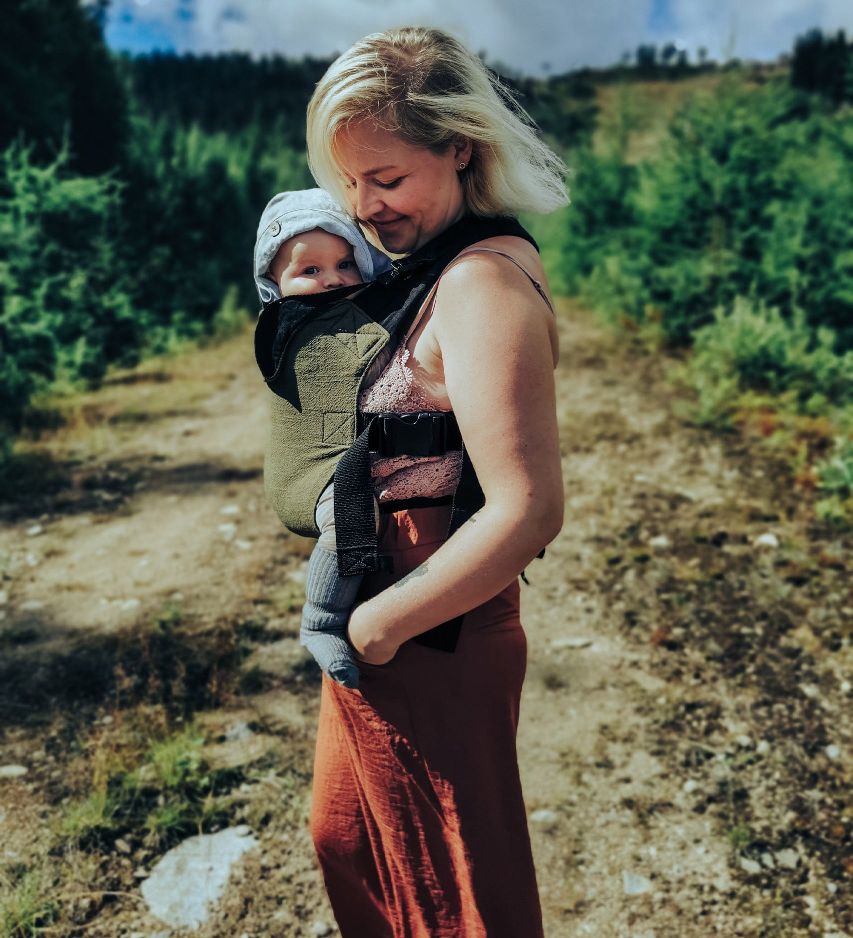 A mother and baby standing outdoors. Mother is carrying the bab in the Integra khaki texture linen baby carrier available at a Babipur. 
