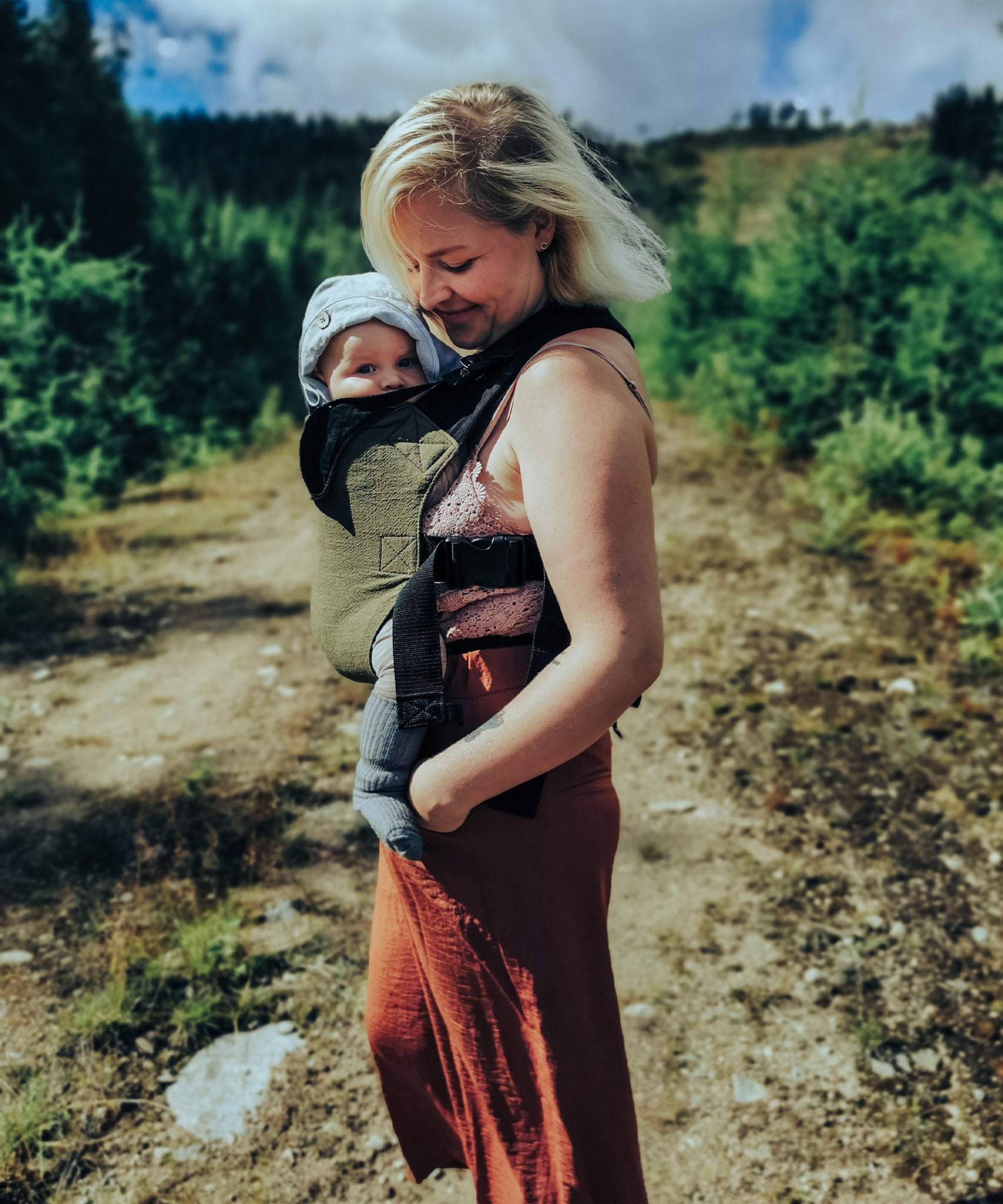 A mother and baby standing outdoors. Mother is carrying the bab in the Integra khaki texture linen baby carrier available at a Babipur. 
