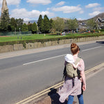 person babywearing on the back using an Integra baby carrier in a sage green colour way