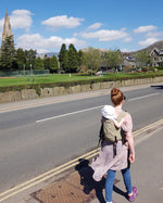 person babywearing on their back using an Integra baby carrier in a sage green colour