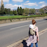person babywearing on their back using an Integra baby carrier in a sage green colour