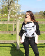 person babywearing on their front using an Integra baby carrier with a geometric design