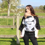 person babywearing on their front using an Integra baby carrier with a geometric design