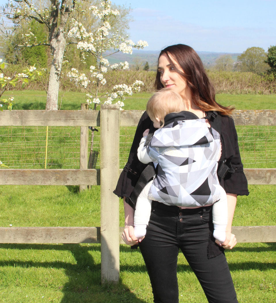 person babywearing on their front using an Integra baby carrier with a geometric design