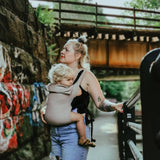 A person wearing the Integra Size 3 Taupe Regular Strap Baby Carrier with a child inside