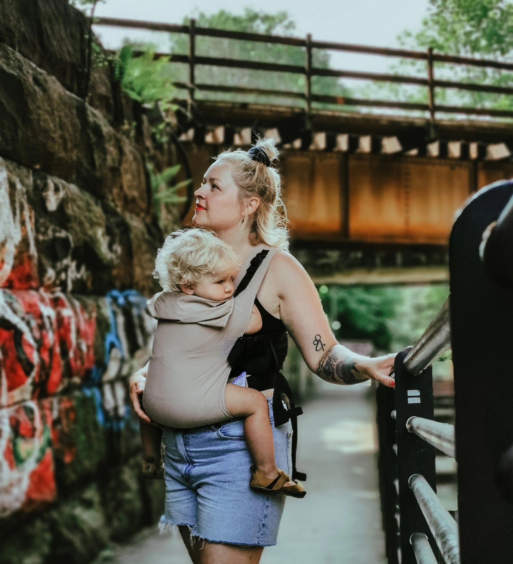 A person wearing the Integra Size 3 Taupe Regular Strap Baby Carrier with a child inside