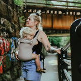 person babywearing on their front using a taupe coloured Integra baby carrier