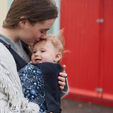 A mother carrying a baby in a Integra Copenhagen flower carrier available at Babipur.