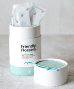 Jack N' Jill Friendly Flossers in a 45 Pack tub one has been taken out of the individual packaging and placed on the lid. 