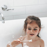 Child in a bath using the wand from the Jack N' Jill Blissful Bubbles Bubble Bath with Bubble Wand