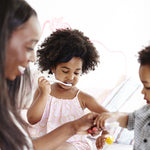 Woman and two children using Jack N Jill toothbrushes and toothpaste in a white room