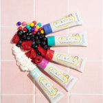 Five tubes of different flavoured Jack n Jill kids natural toothpaste, with fruits and candies to represent their flavours. 