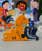 Jig-So Cymraeg Cartref. A Welsh Home themed wooden jigsaw puzzle with painted pieces.The photo shows a close up of the dog shaped piece with the Welsh for for dog ci written ion it. A selection of Welsh Jigsaw puzzles from Alphabet Jigsaws are available at Babipur.