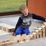 Young boy playing with a wooden ball run made using Just Blocks Smart Lines on a grey carpet