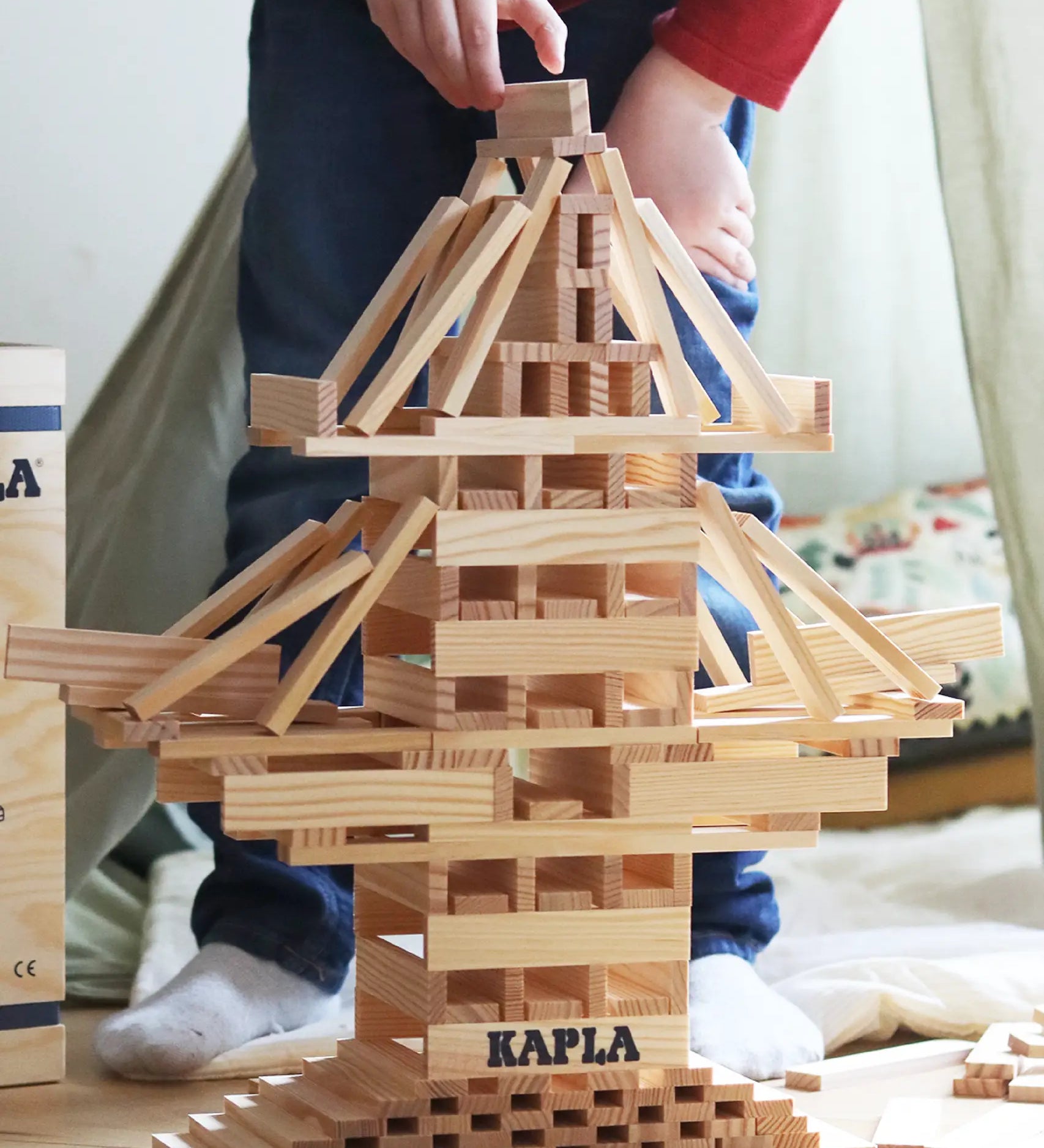 Child building a rocket using the natural Kapla wooden construction planks 