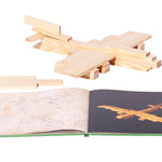 Wooden aeroplane model on a white background next to the Kapla simple architecture art book on a white background