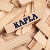 A pile of Kapla unpainted wooden construction planks with one plank showing the brand logo