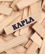 A pile of Kapla unpainted wooden construction planks with one plank showing the brand logo