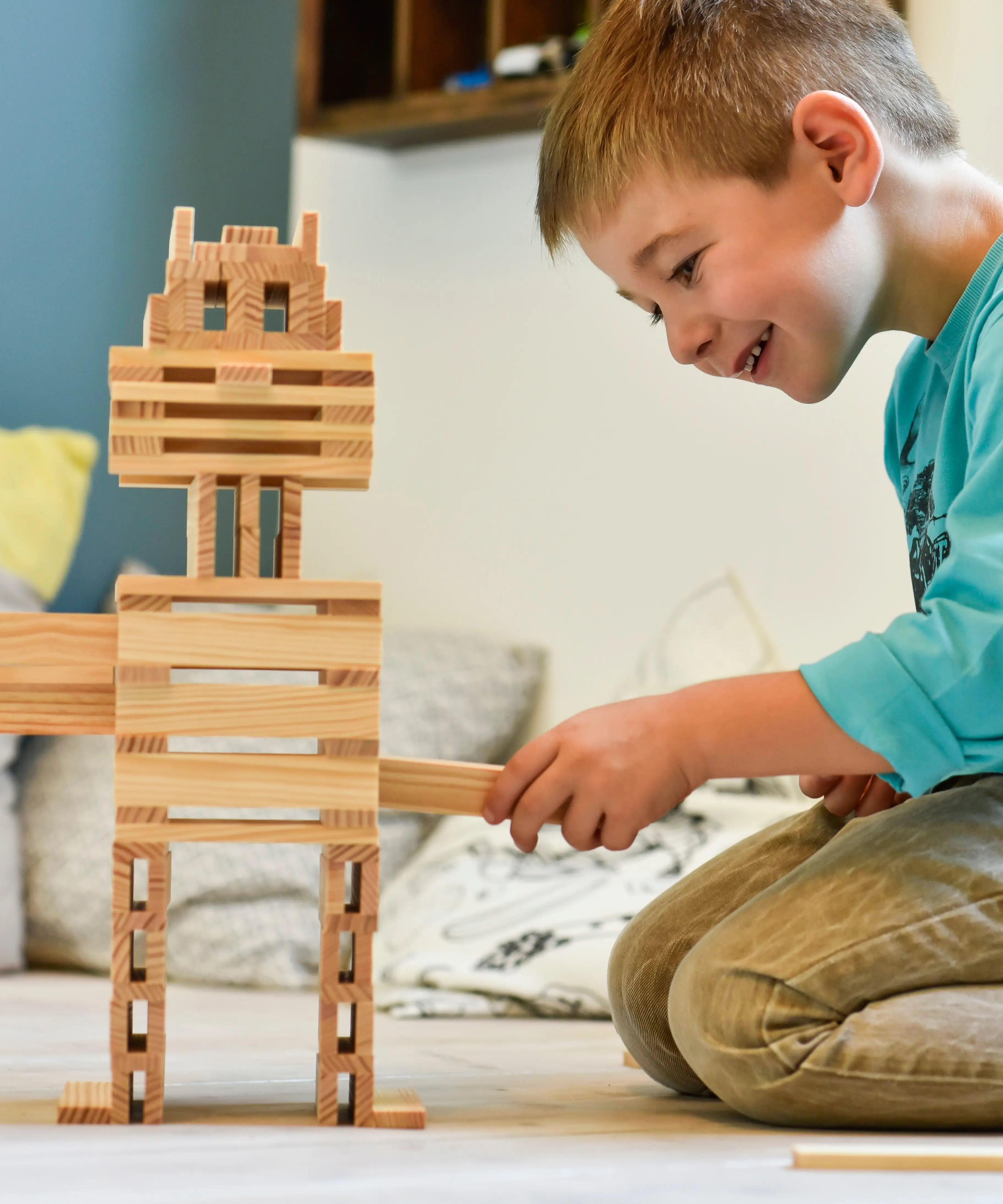 Child building a robot made from the natural Kapla wooden construction planks 